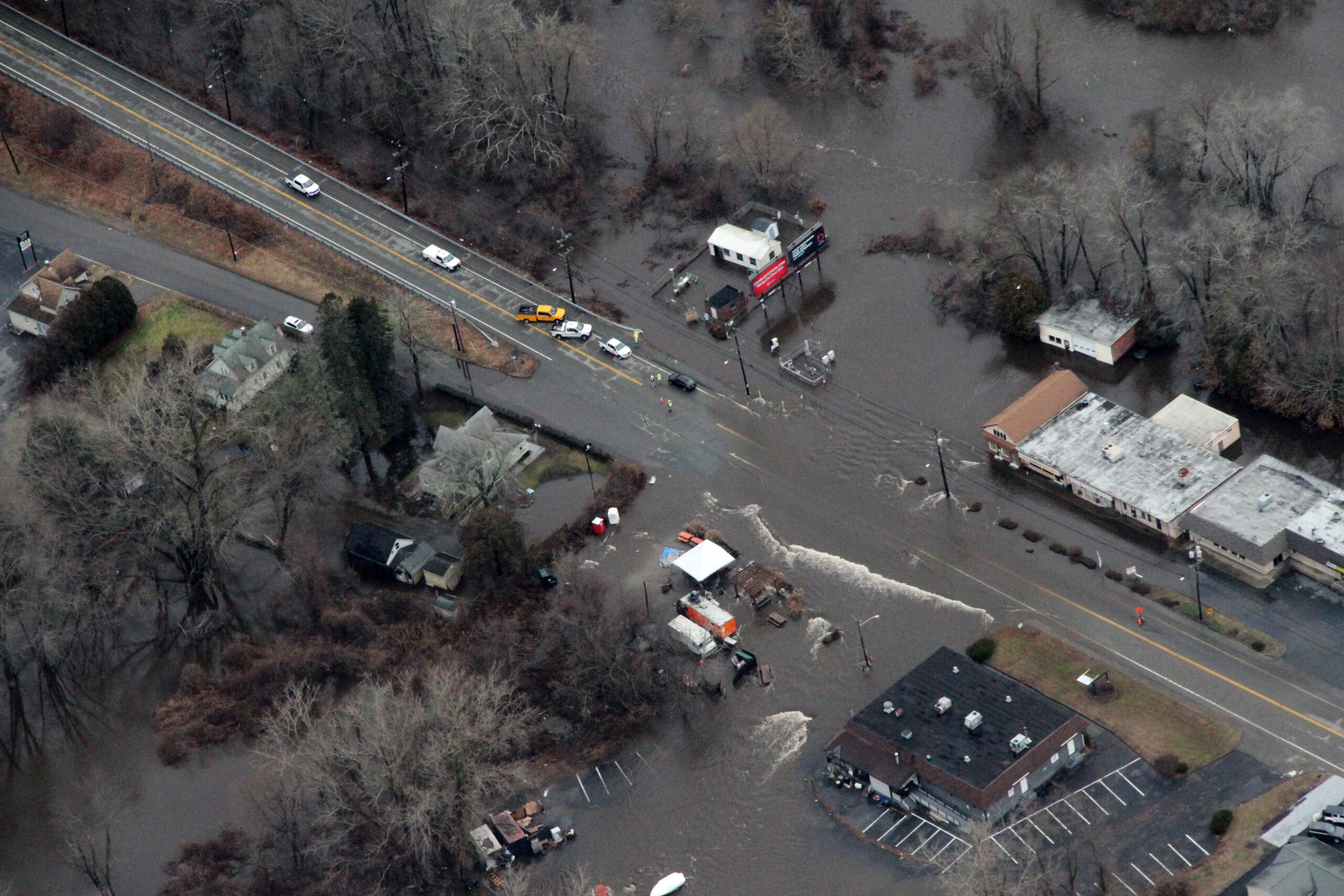 Yantic River flooding during a major storm event with flood waters blocking a roadway and inundating buildings.