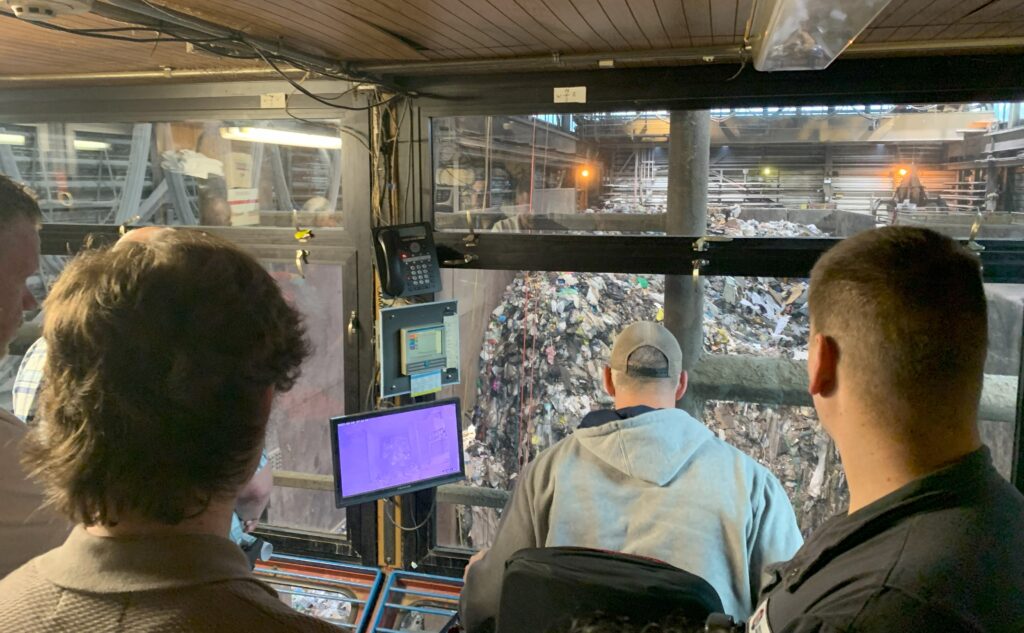 An operator oversees sorting a large pile of trash